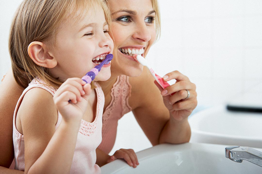 Mother brushes teeth together with her child